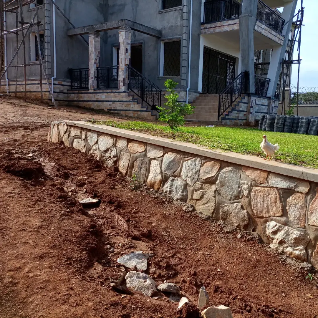 A stone-faced retaining edge defines the green space beside the house.