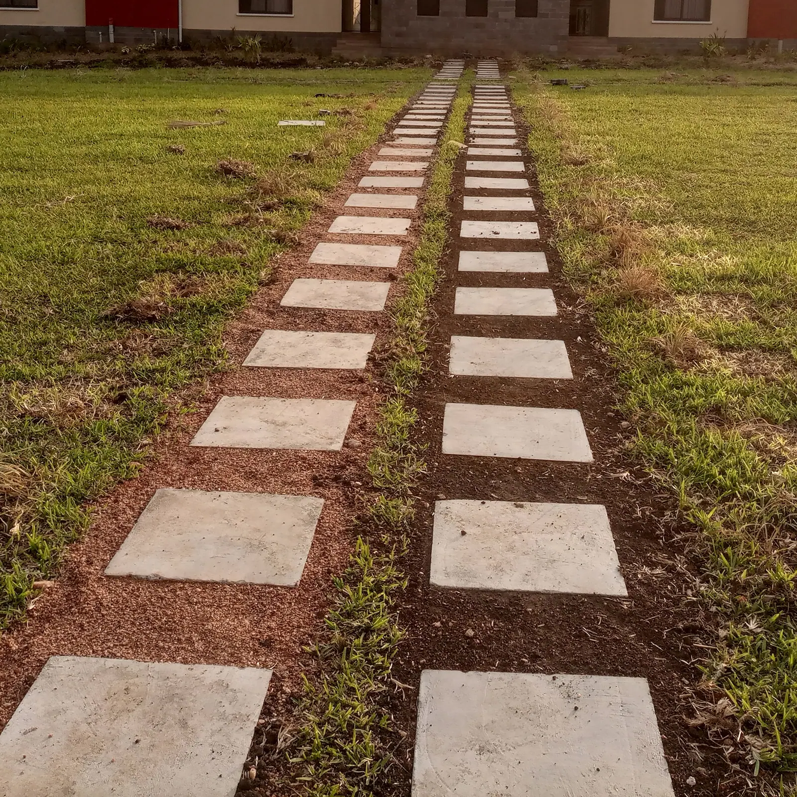 Two rows of pale stepping stones lead through the lawn towards the house.
